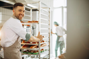 Bakers Rolling Trolleys of Bread into a Fridge