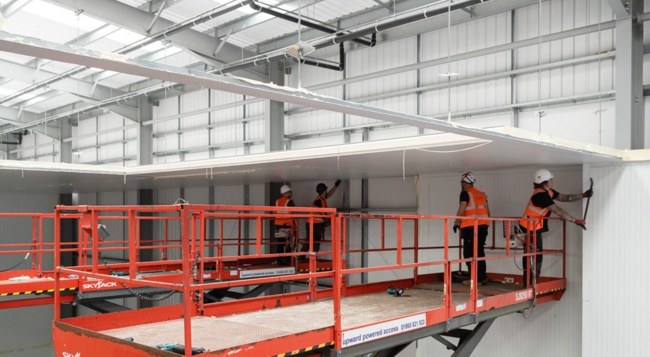 Cold room workers on a scissor lift installing a new walk in fridge